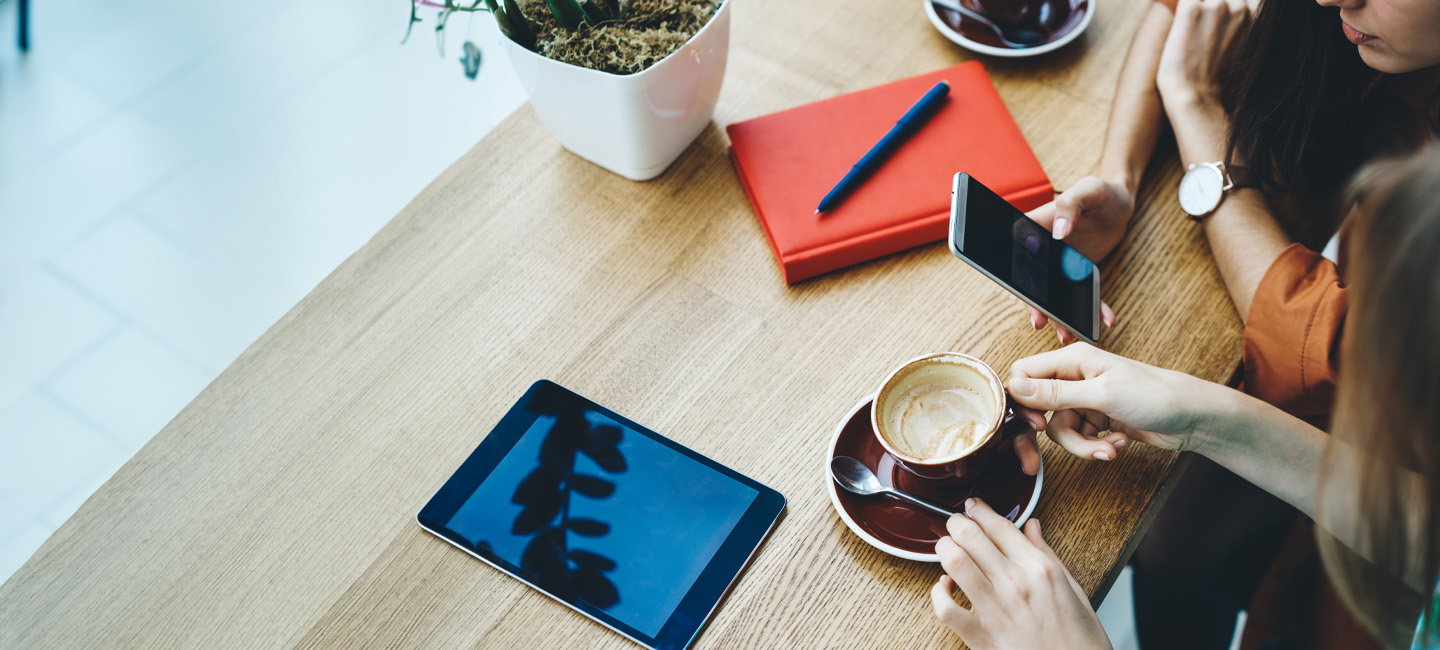 Pessoas num café, a verem algo no telemóvel