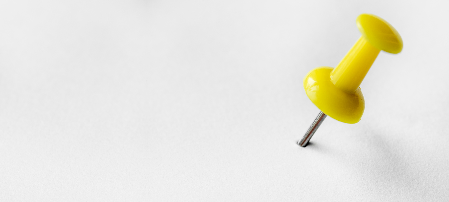 Alfinete amarelo espetado num papel branco.