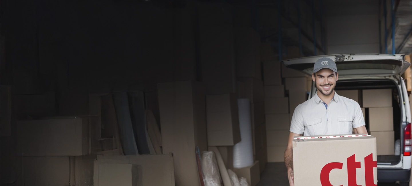 Homem a trabalhar na secretária com um computador portátil e uma caixa de envio Expresso